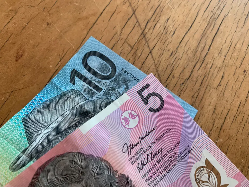 Australian 5 and 10 dollar notes on a wooden surface